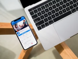 laptop and phone with facebook open in phone